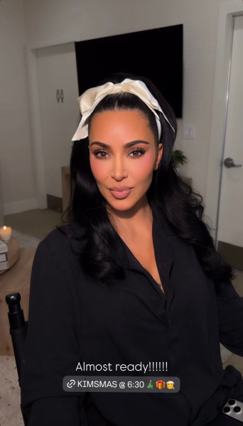Kim Kardashian wears her hair in loose curls tied with a large ivory bow at the top of her head.
